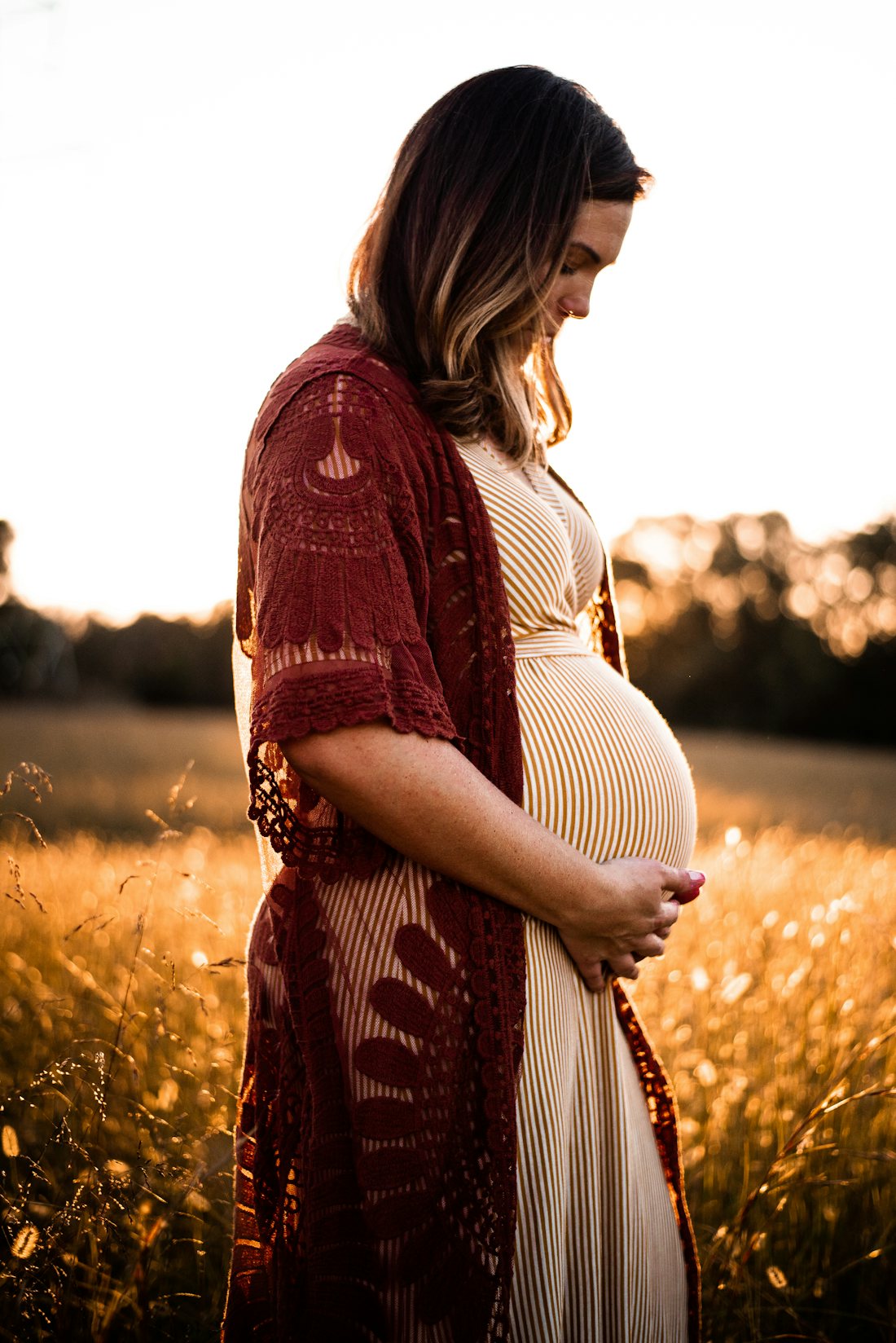 Expectant mother cradling her baby bump in warm evening light